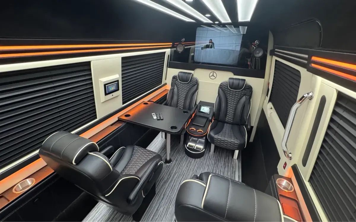 Cabin of the Mercedes-Benz Sprinter 7 executive lounge: facing captain's chairs, conference table and screen